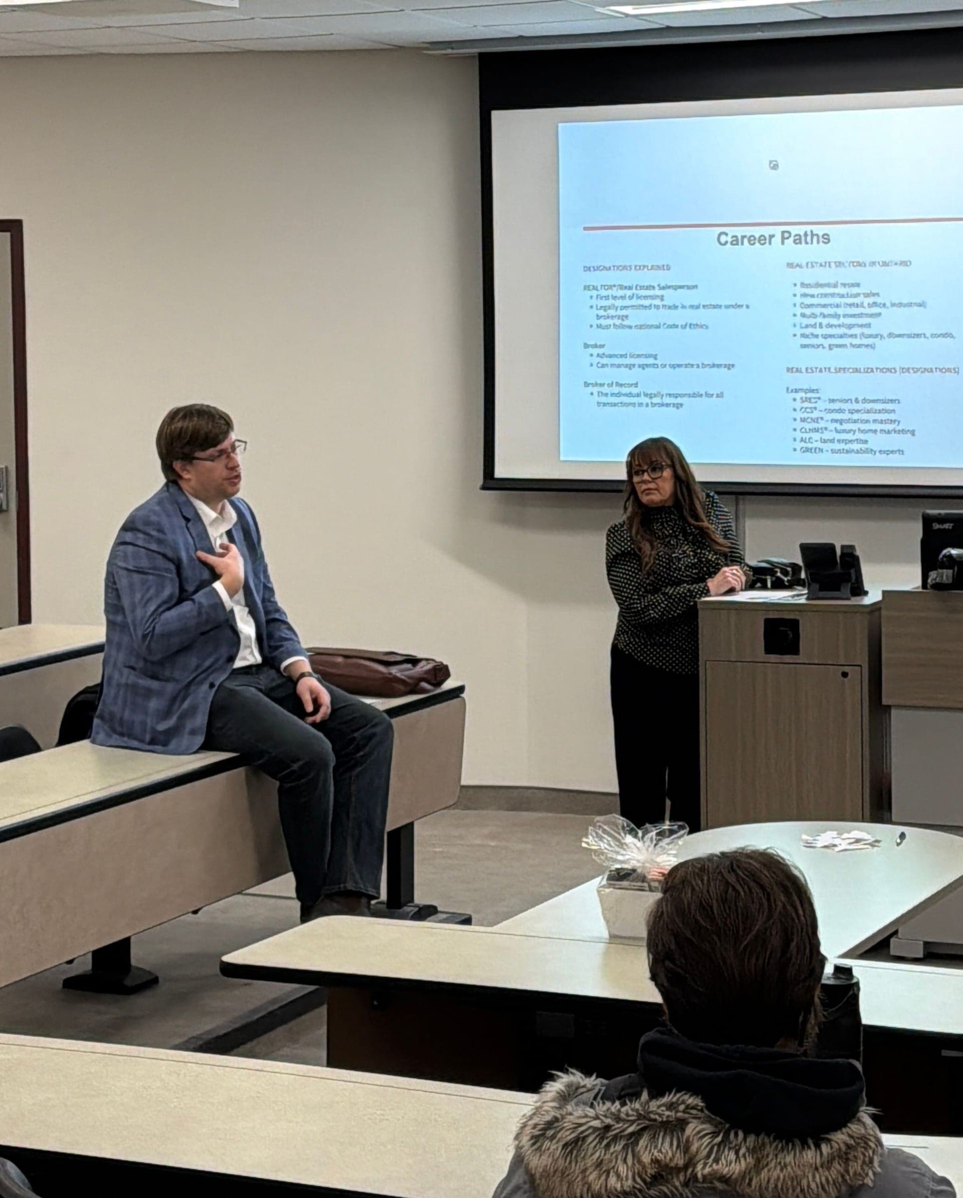 Nic Von Bredow talks to the room from the front desk, with Stacey Adamson beside the projected Career Paths slide.