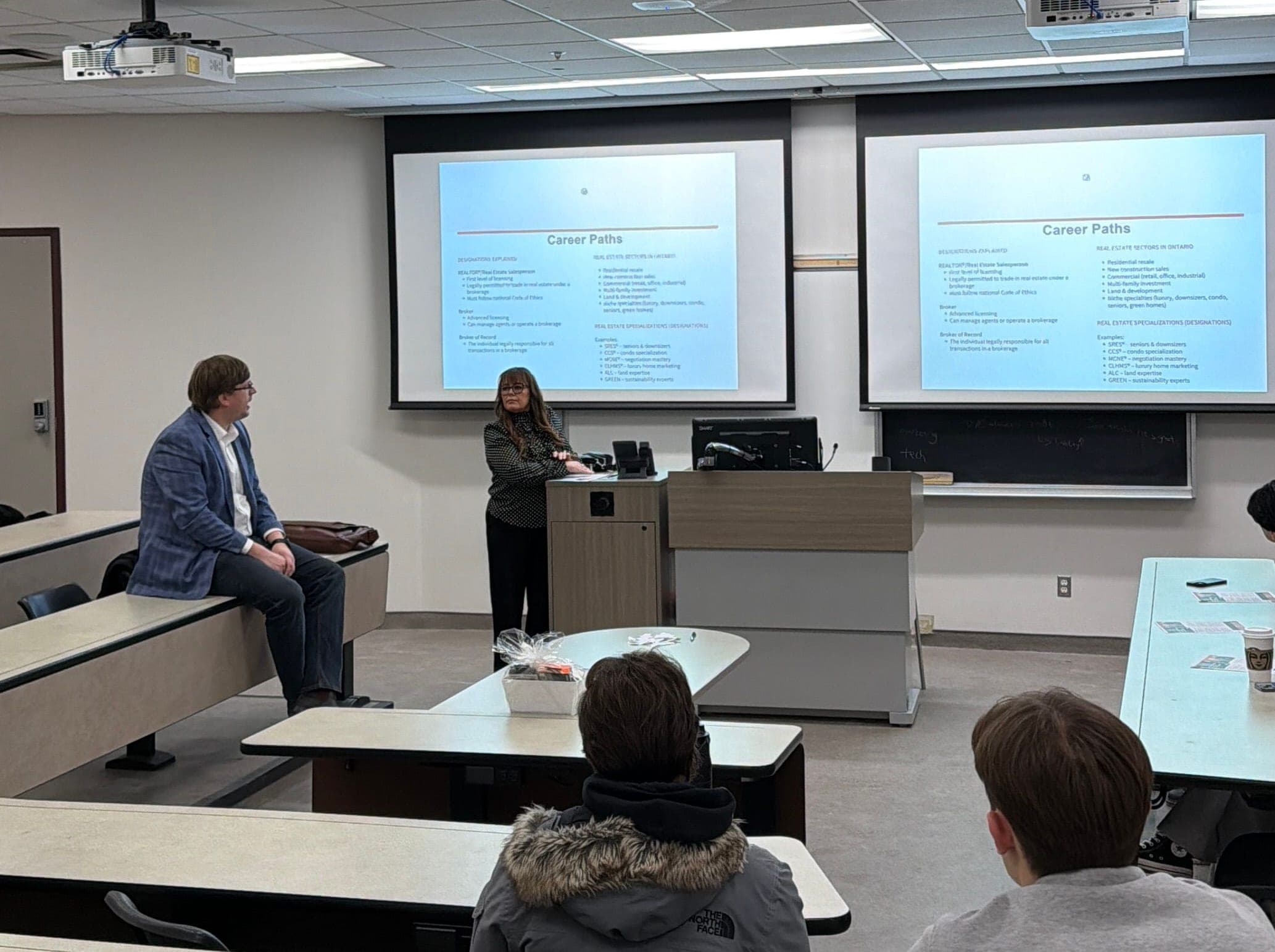 Stacey Adamson presents a Career Paths slide at the podium as Nic Von Bredow sits at the front of the room and students look on.